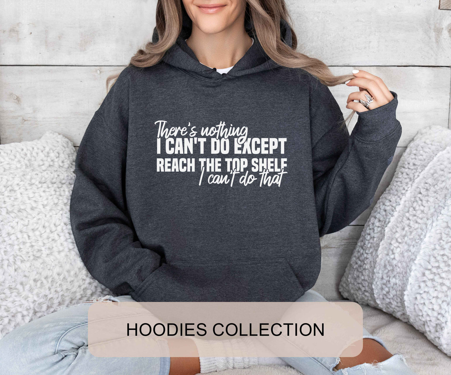 A dark heather color hoodie with the saying "There's nothing I can't do except reach the top shelf I can't do that"