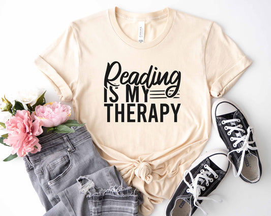 A natural color shirt with the saying "Reading is my therapy"