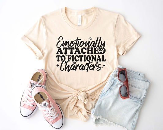 A natural color shirt with the saying "Emotionally attached to fictional characters"