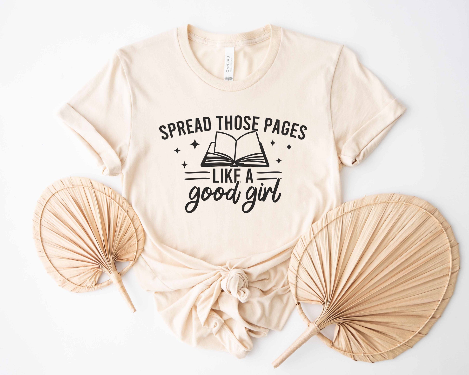 Natural t-shirt with text 'Spread those pages like a good girl' on a white background with decorative fans.