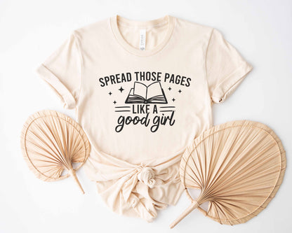Natural t-shirt with text 'Spread those pages like a good girl' on a white background with decorative fans.