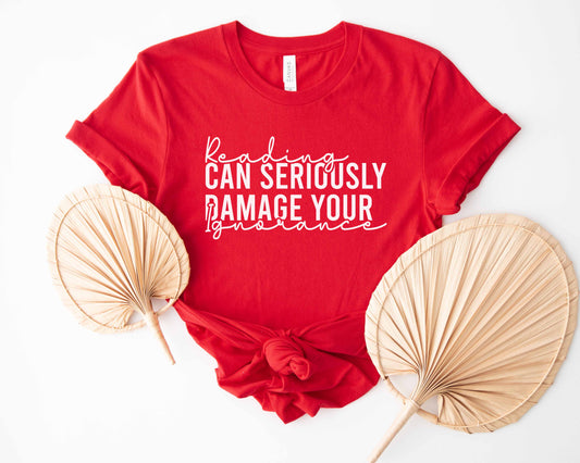 A red color shirt with the saying "Reading can seriously damage your ignorance"