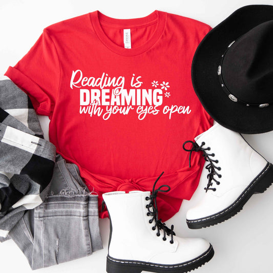A red color shirt with the saying "Reading is dreaming with your eyes open"