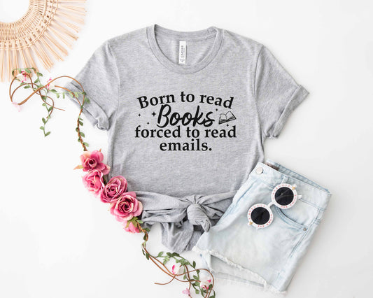Athletic heather t-shirt with 'Born to read Books forced to read emails' text, paired with denim shorts and sunglasses on a white background.
