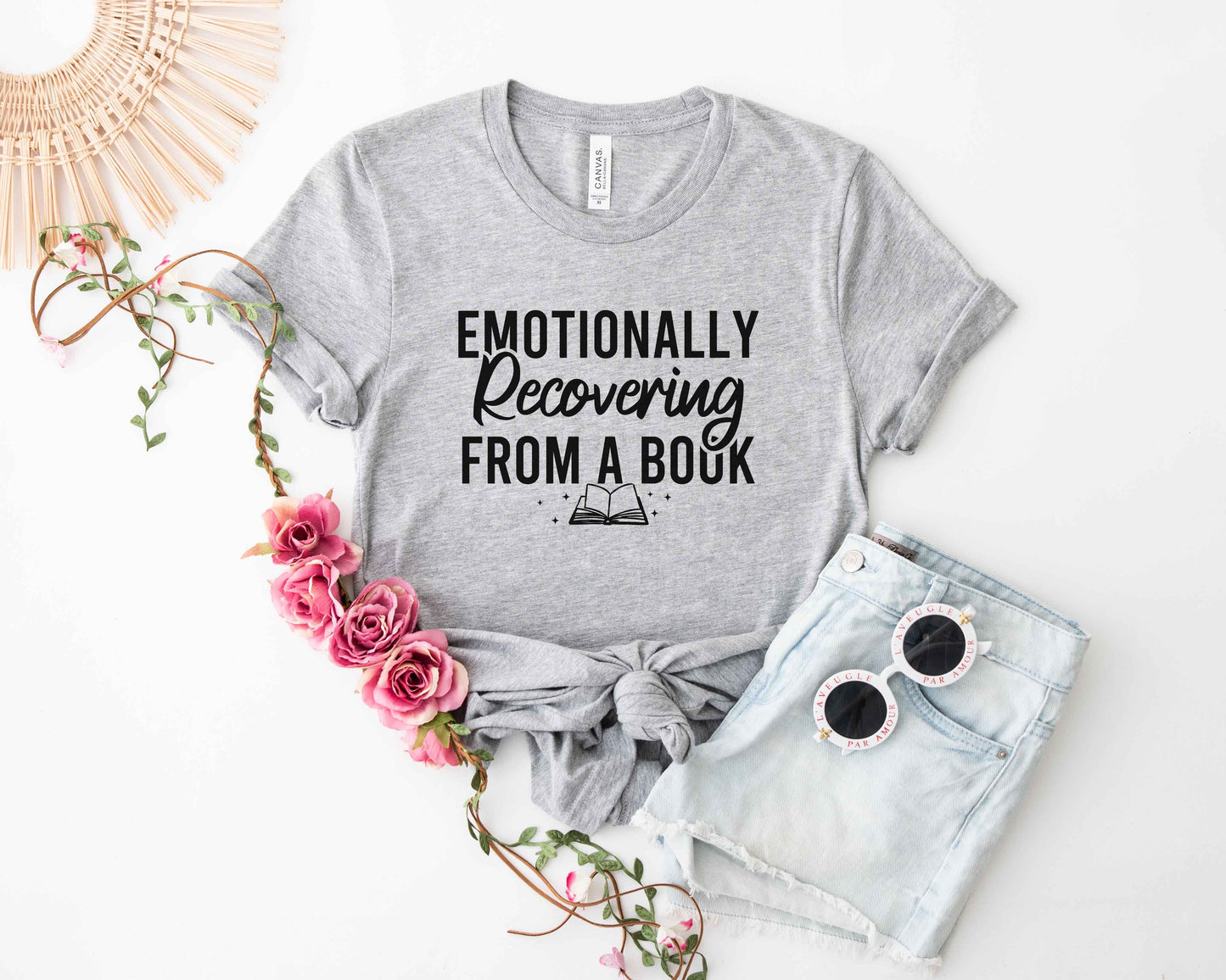 Athletic heather t-shirt with 'Emotionally Recovering from a Book' text, sunglasses, and flowers on a white background