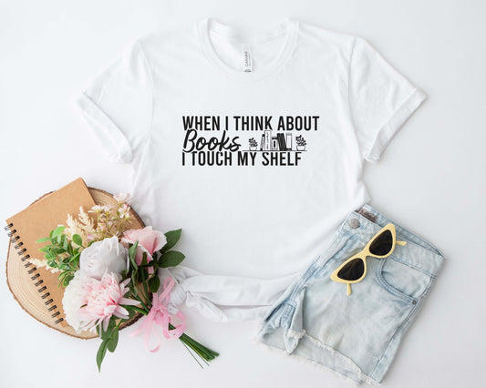 A white color shirt with the saying "When i think about books i touch my shelf"