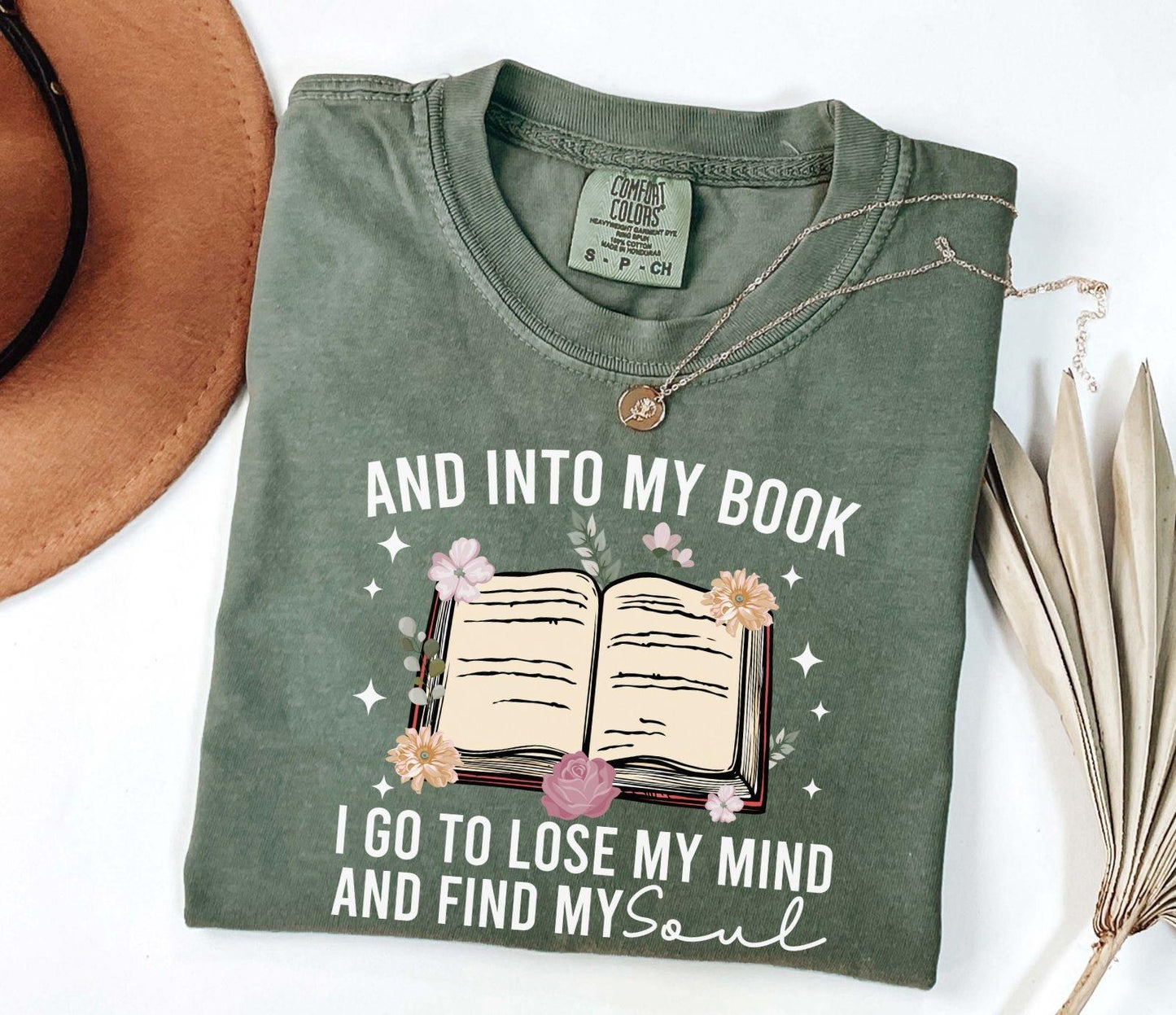 A comfort colors shirt with the saying "And into my book I go to lose my mind and find my soul"
