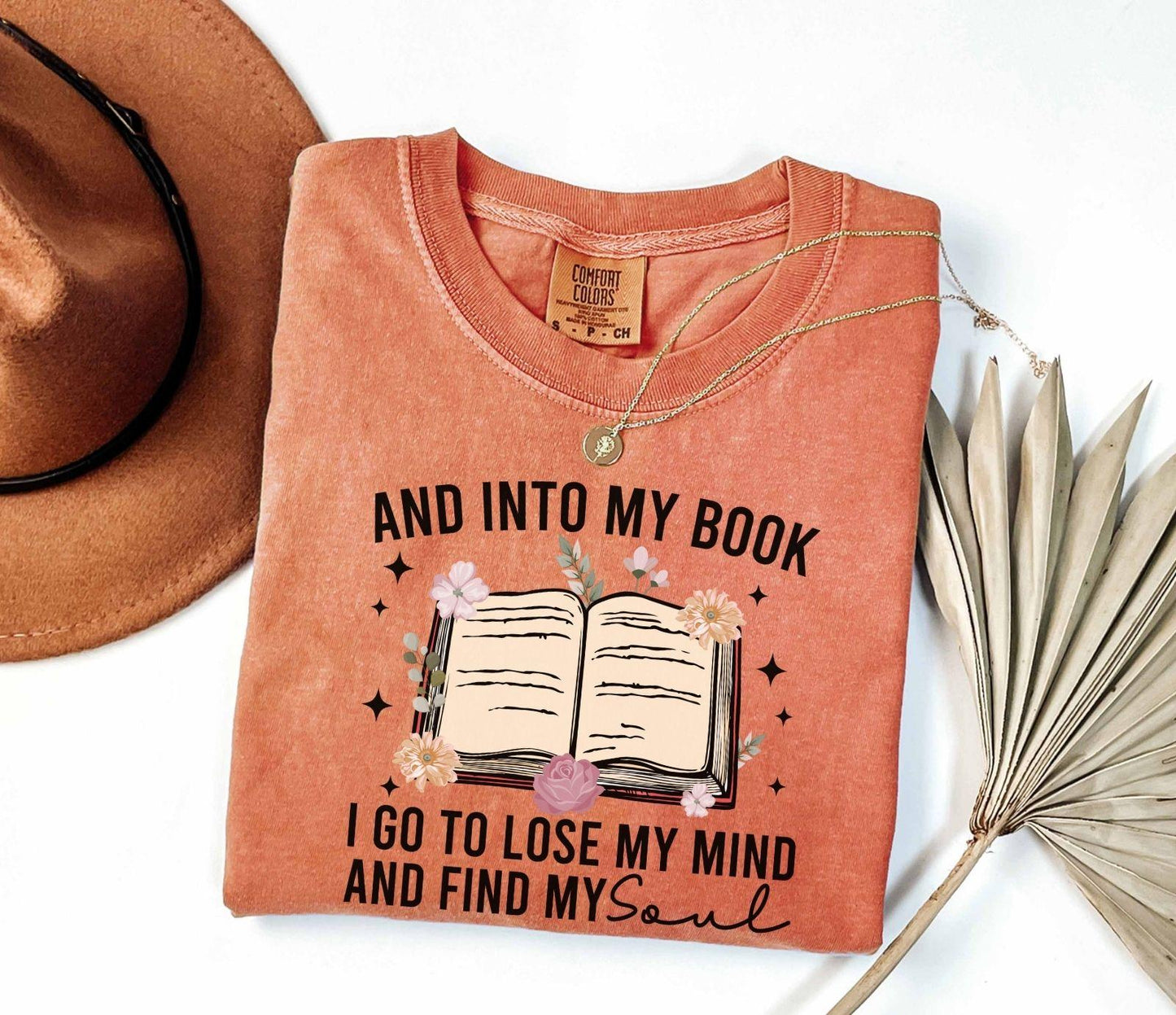 A comfort colors shirt with the saying "And into my book I go to lose my mind and find my soul"