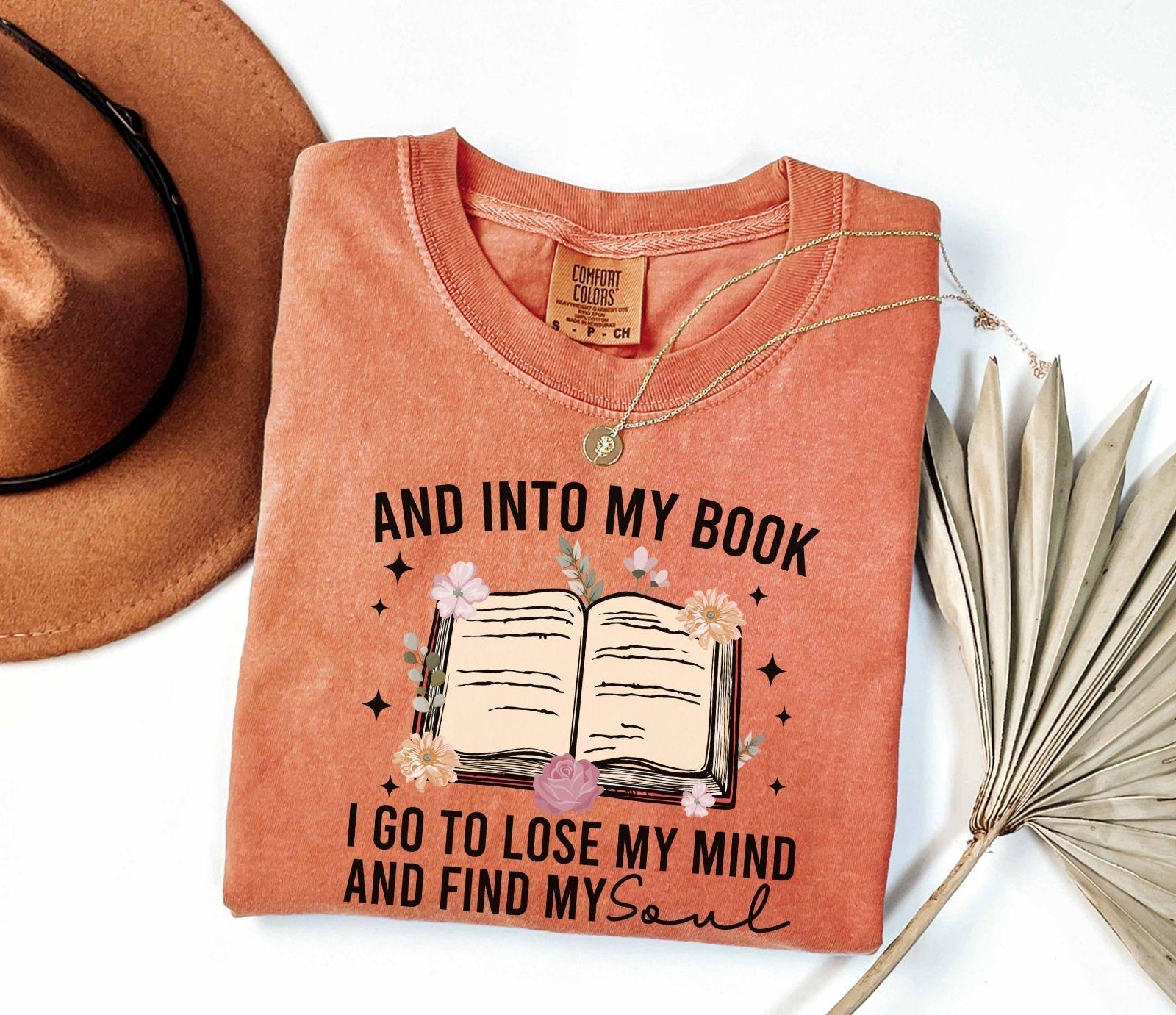 A comfort colors shirt with the saying "And into my book I go to lose my mind and find my soul"