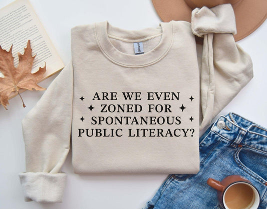 A Gildan 18000 sweatshirt with the saying "Are We Even Zoned For Spontaneous Public Literacy"