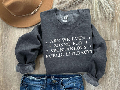A Gildan 18000 sweatshirt with the saying "Are We Even Zoned For Spontaneous Public Literacy"