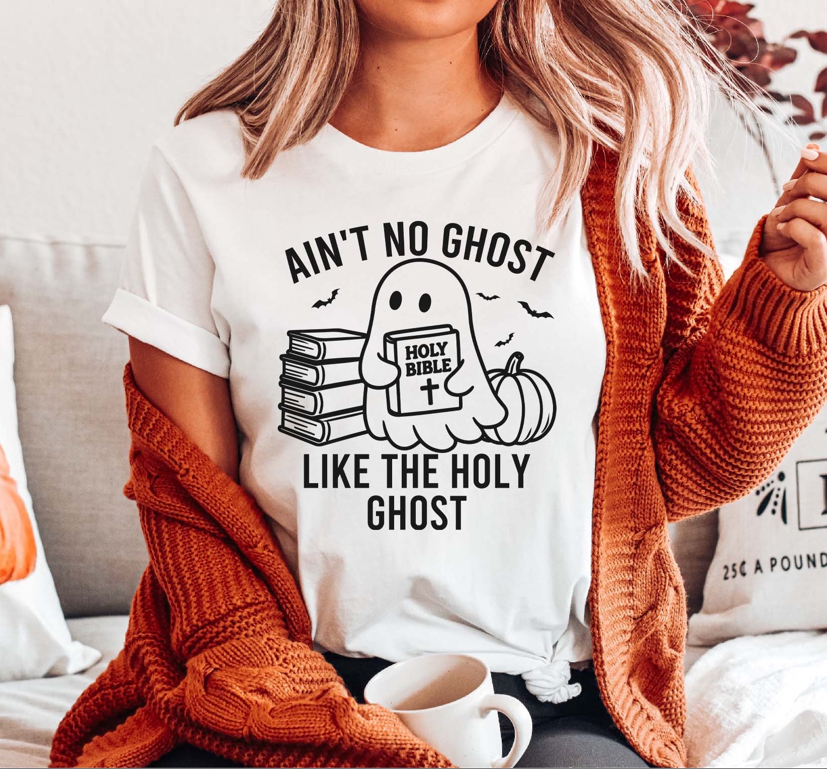 Person wearing a white t-shirt with a ghost graphic and text, sitting on a couch.