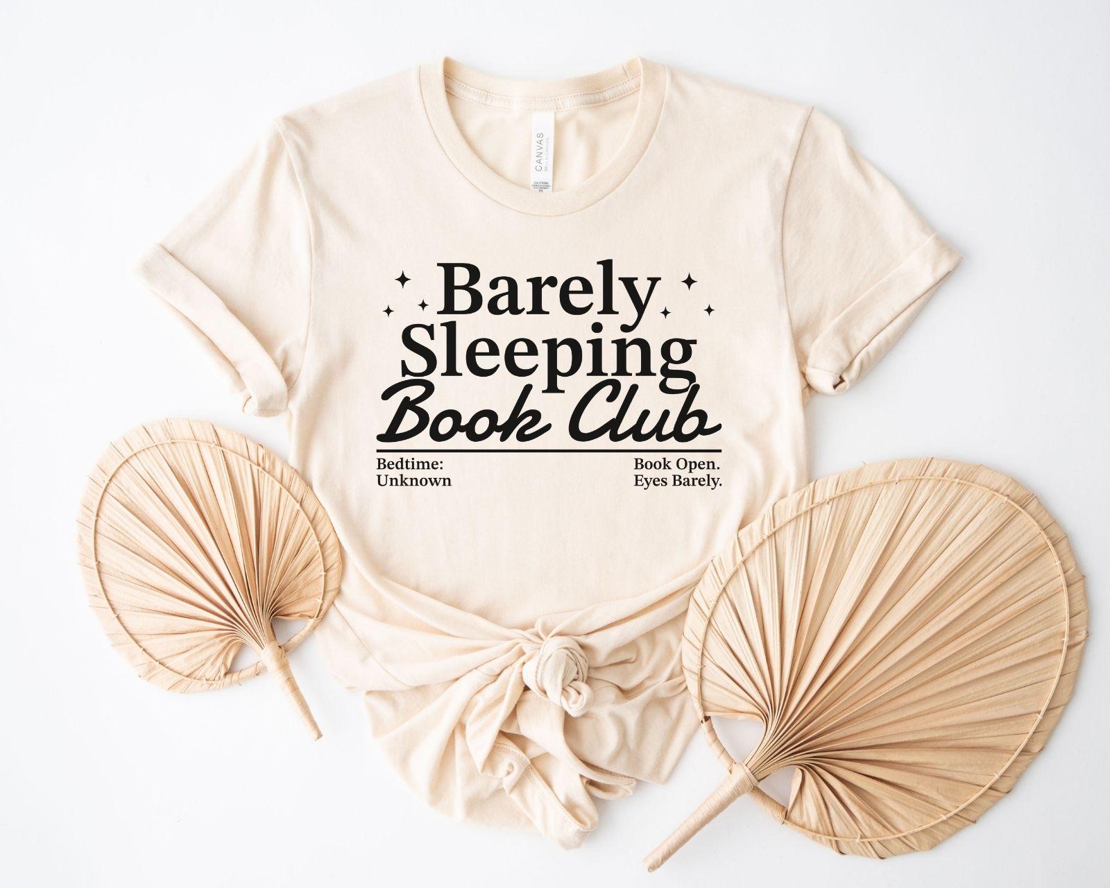A bella canvas 3001 shirt with the saying "Barely sleeping book club"