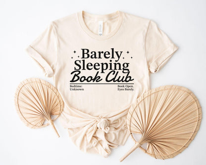 A bella canvas 3001 shirt with the saying "Barely sleeping book club"
