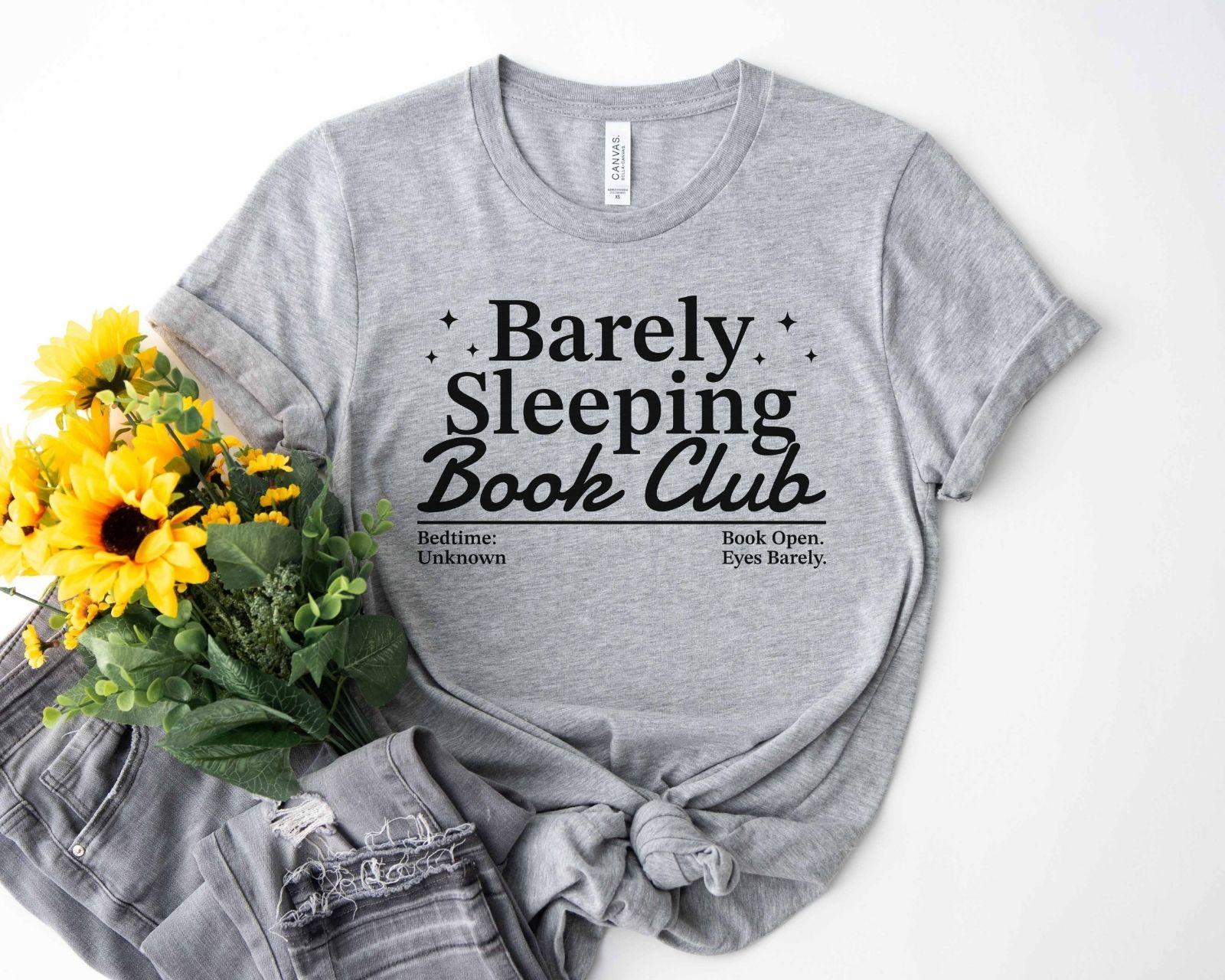 A bella canvas 3001 shirt with the saying "Barely sleeping book club"