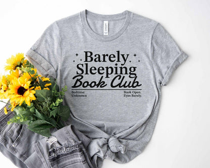 A bella canvas 3001 shirt with the saying "Barely sleeping book club"