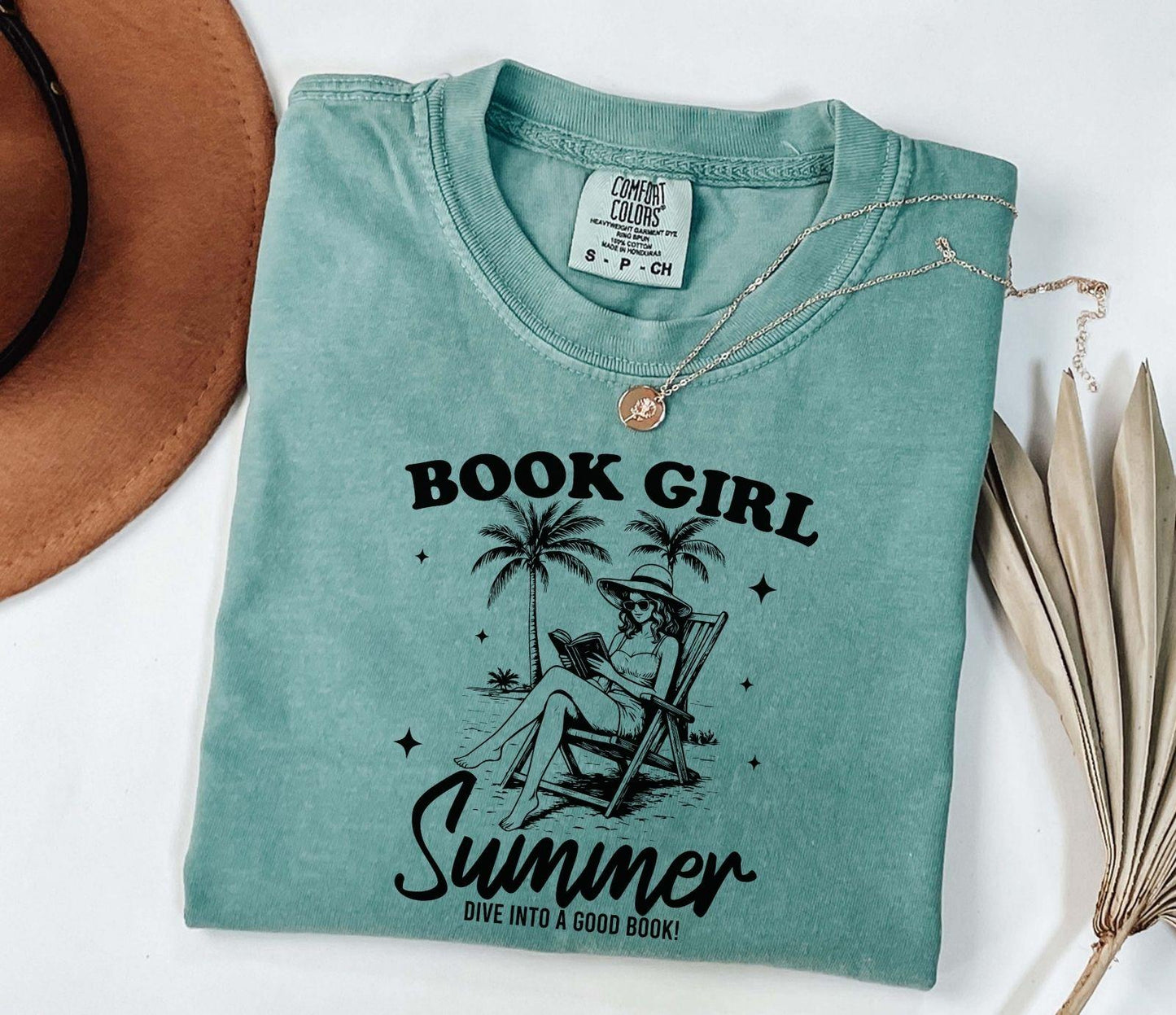 A comfort colors shirt with the saying "book girl summer dive into a good book"
