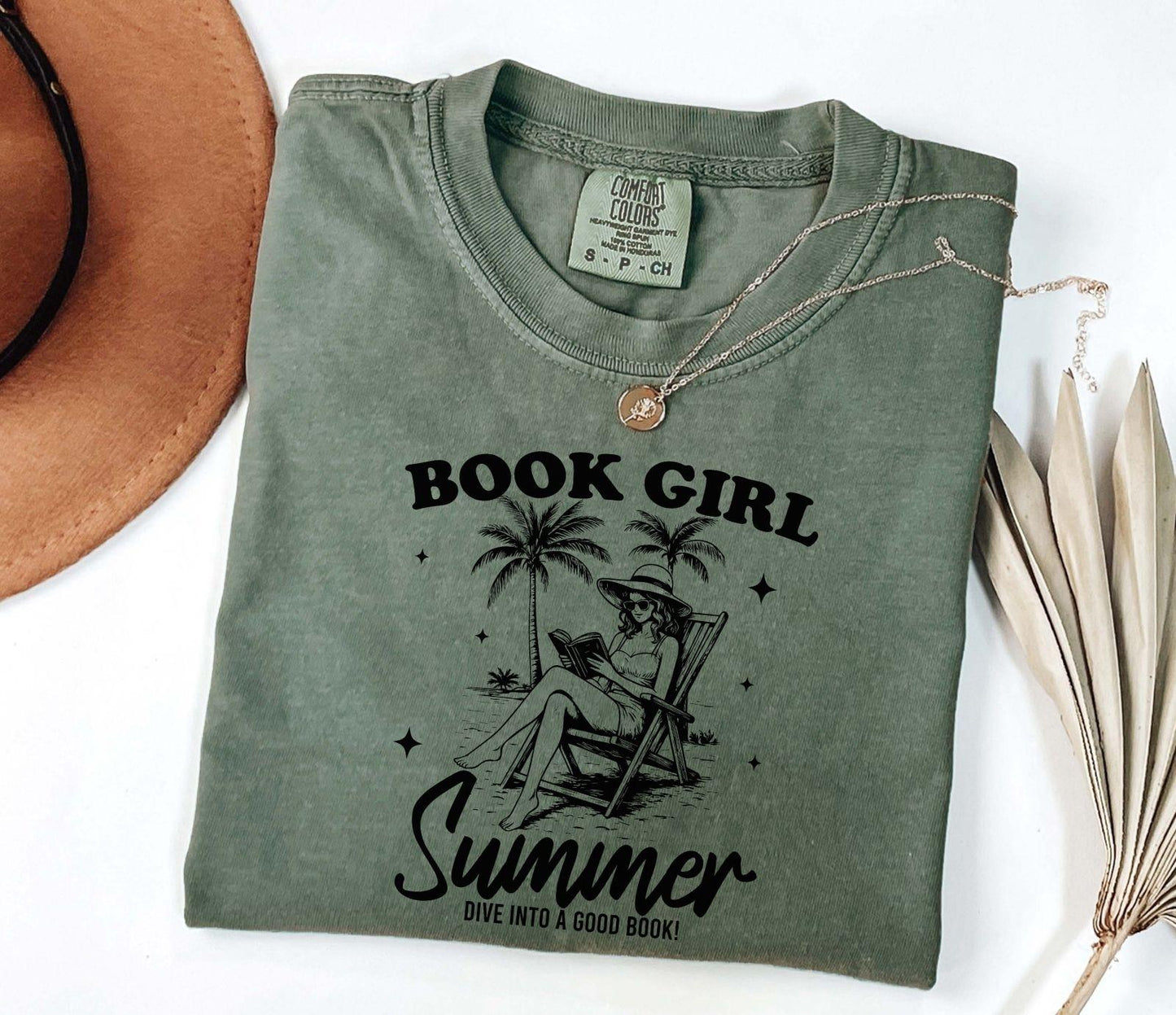 A comfort colors shirt with the saying "book girl summer dive into a good book"