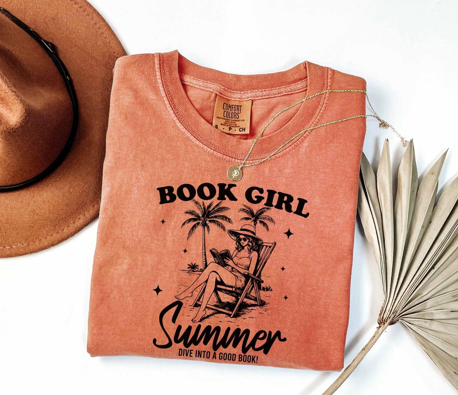 A comfort colors shirt with the saying "book girl summer dive into a good book"