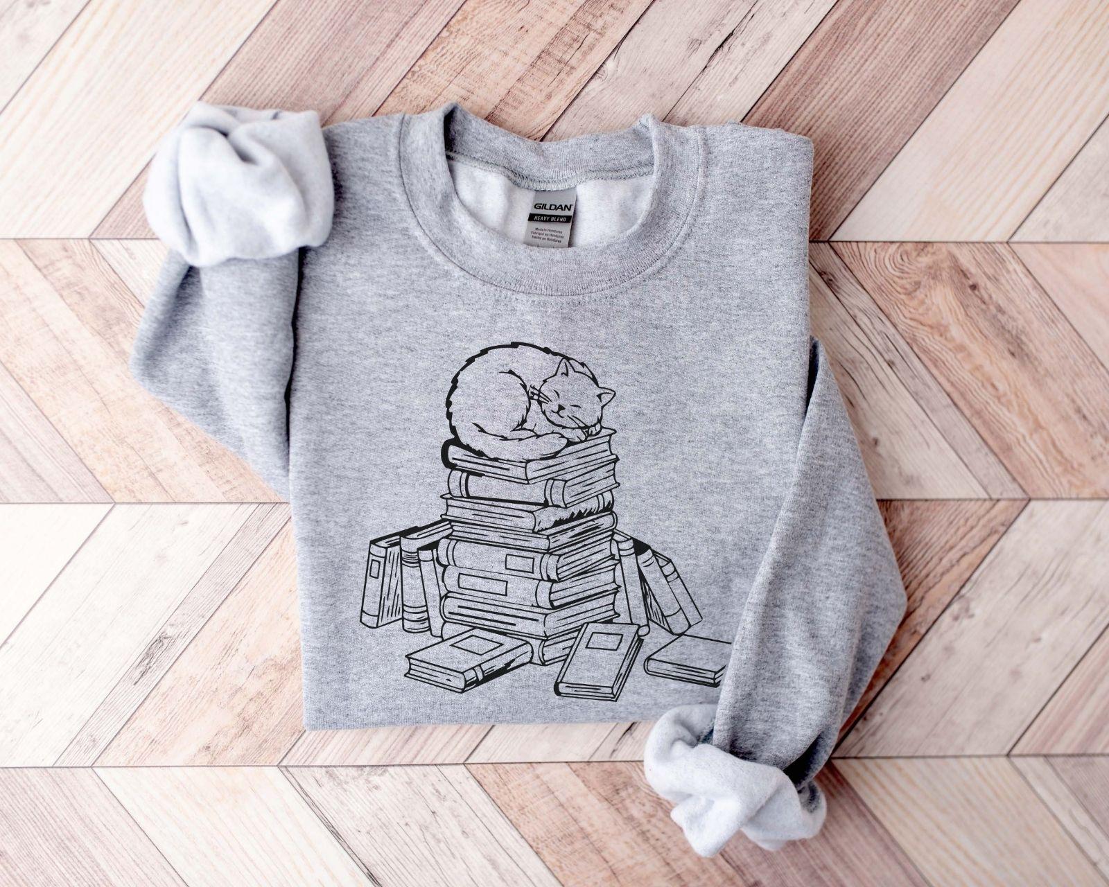 A Gildan 18000 sweatshirt with the saying "a cat with books"