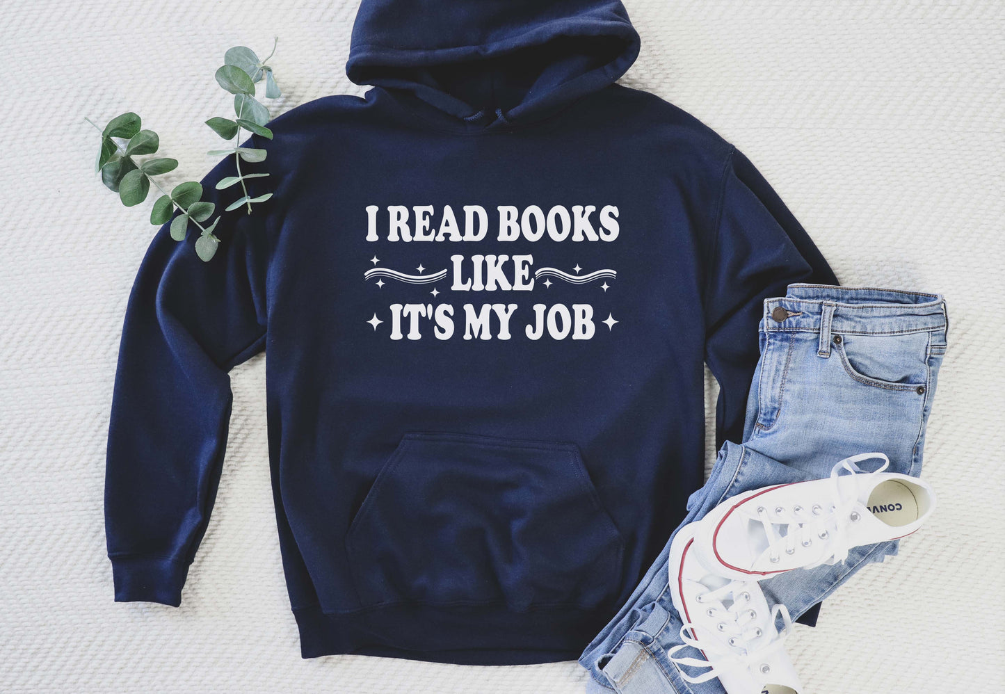 Navy blue hoodie with 'I Read Books Like It's My Job' text, paired with jeans and sneakers on a light background