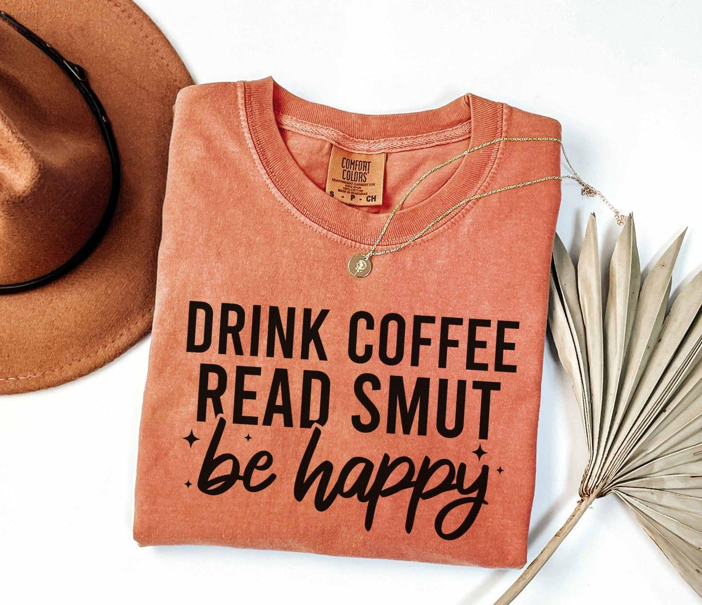 A comfort colors shirt with the saying "Drink coffee read books be happy"