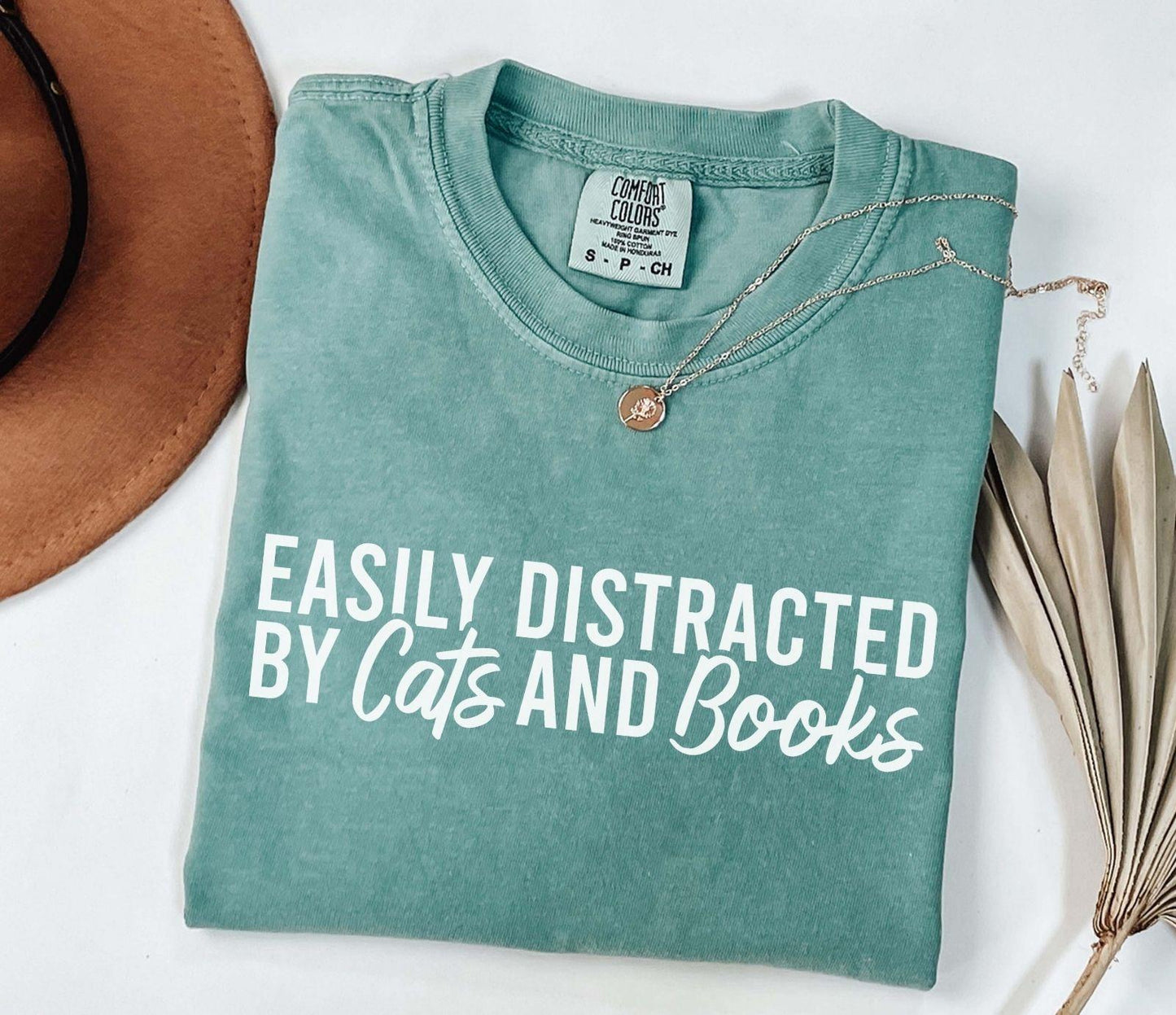 A comfort colors® shirt with the saying "Easily distracted by cats and books"