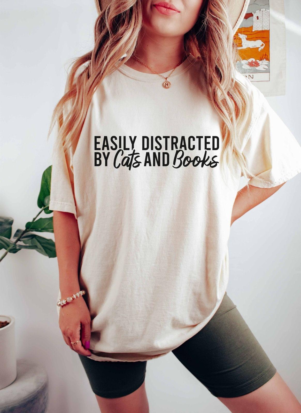 A comfort colors® shirt with the saying "Easily distracted by cats and books"