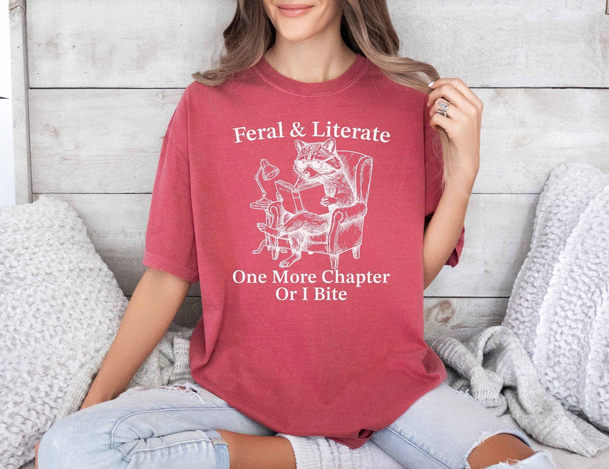 A comfort colors® shirt with the saying "Feral And Literate One More Chapter Or I Bite"