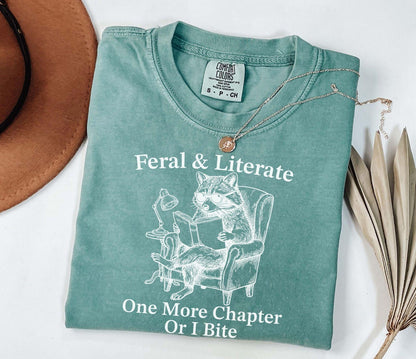 A comfort colors® shirt with the saying "Feral And Literate One More Chapter Or I Bite"