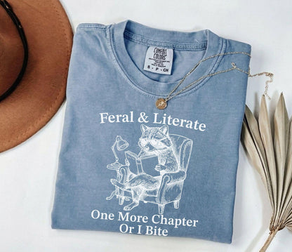 A comfort colors® shirt with the saying "Feral And Literate One More Chapter Or I Bite"