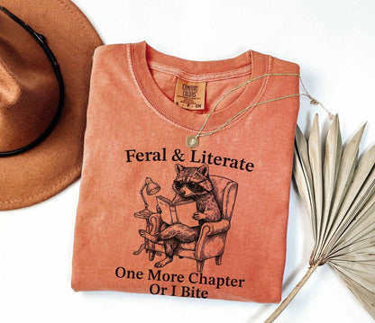 A comfort colors® shirt with the saying "Feral And Literate One More Chapter Or I Bite"