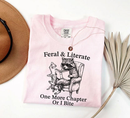 A comfort colors® shirt with the saying "Feral And Literate One More Chapter Or I Bite"