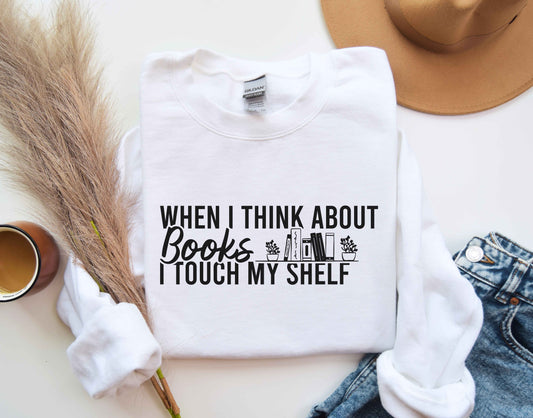 A white color sweatshirt with the saying "When i think about books i touch my shelf"