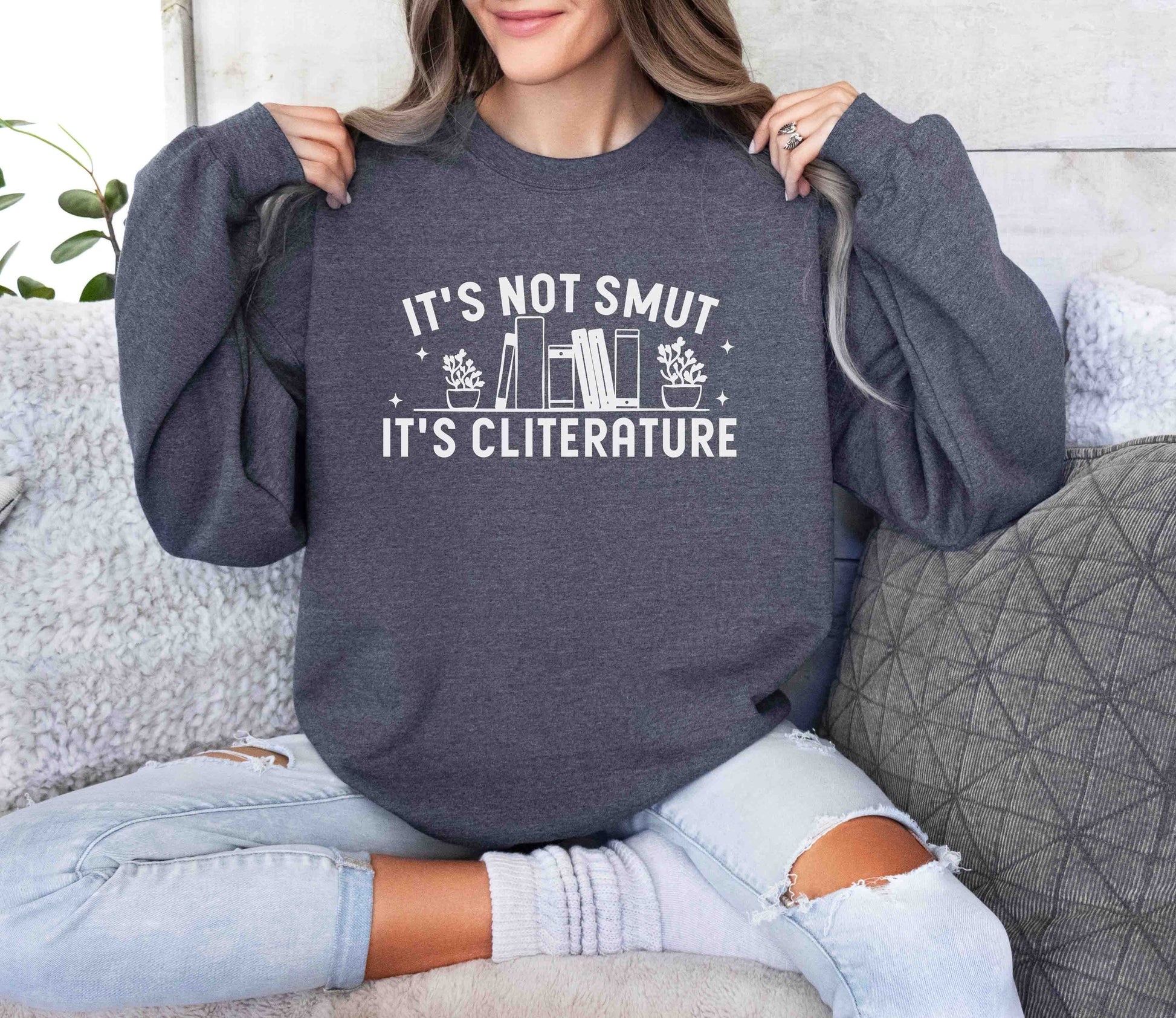 Person wearing a dark heather sweatshirt with text sitting on a couch.