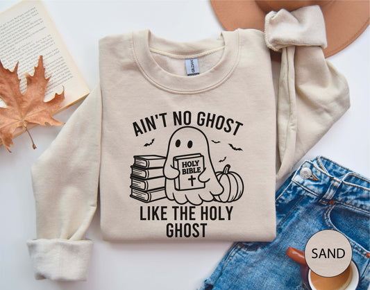 sand sweatshirt with ghost graphic and text on a white surface with autumn leaves and jeans.