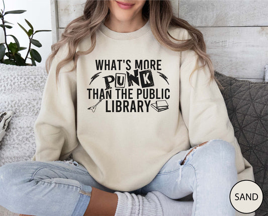 Person wearing a sand sweatshirt with text sitting on a couch.