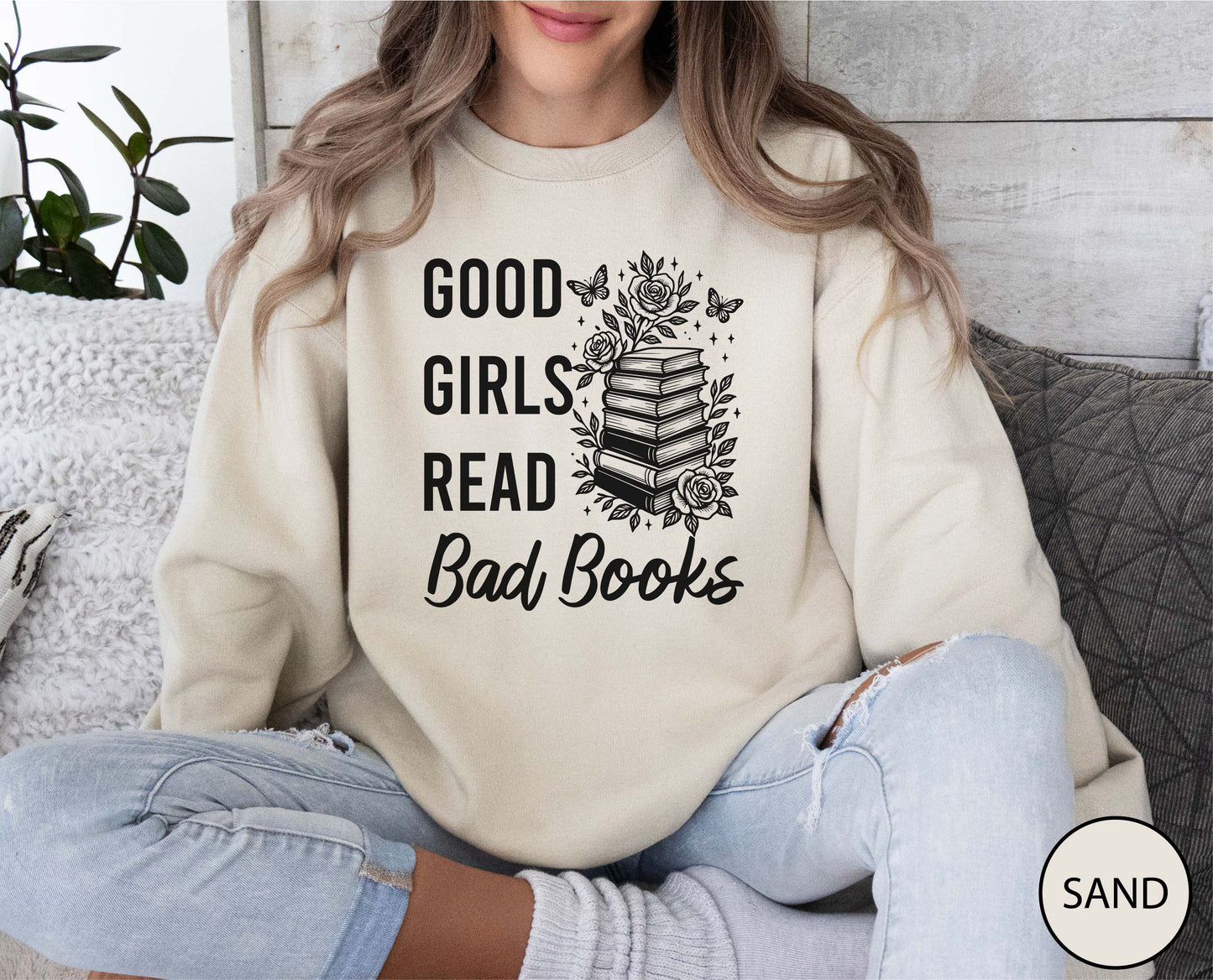 Person wearing a sand sweatshirt with 'Good girls read bad books' text and book graphic.