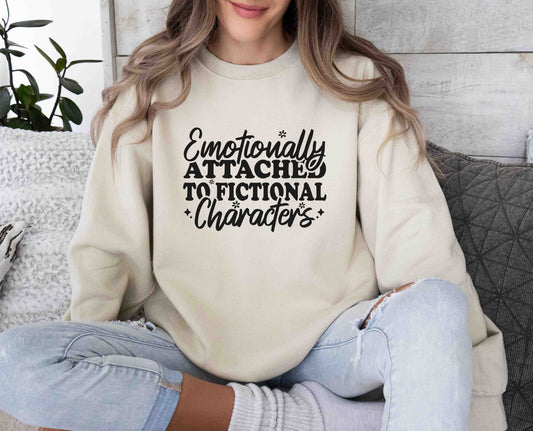 A sand color sweatshirt with the saying "Emotionally attached to fictional characters"