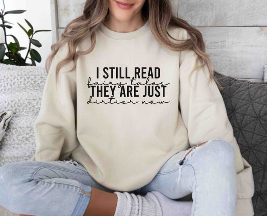 A sand color sweatshirt with the saying "I still read fairy tales they are just dirtier now"