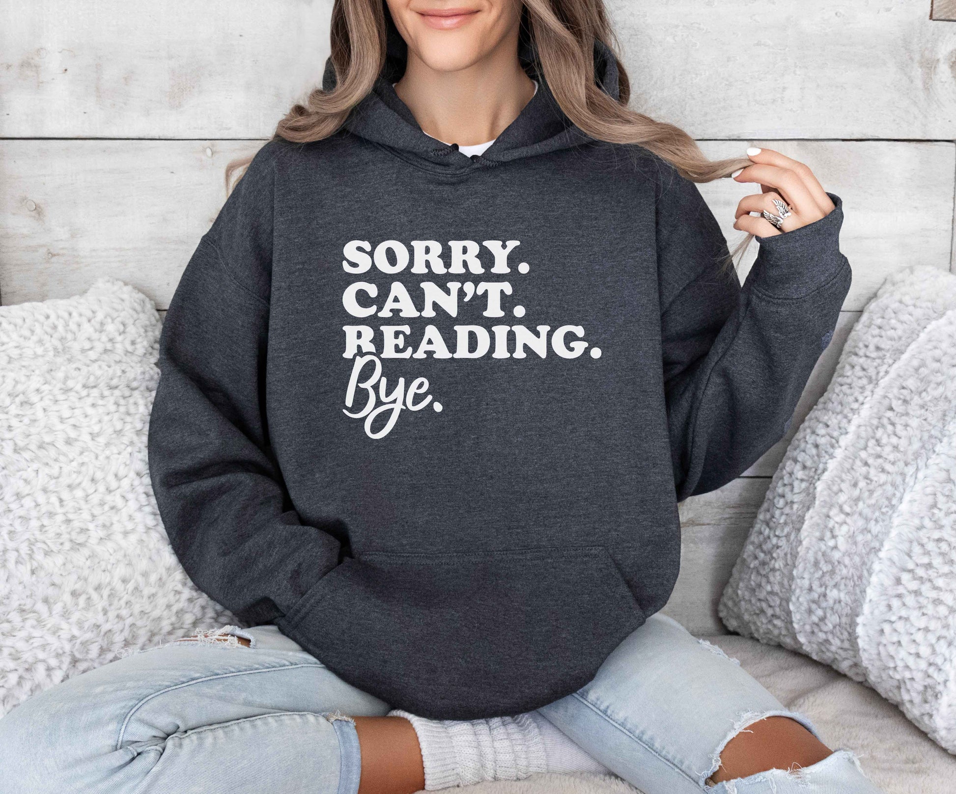 Person wearing a dark heather hoodie with text sitting on a couch.