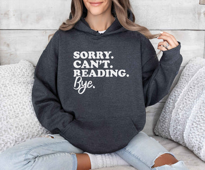 Person wearing a dark heather hoodie with text sitting on a couch.
