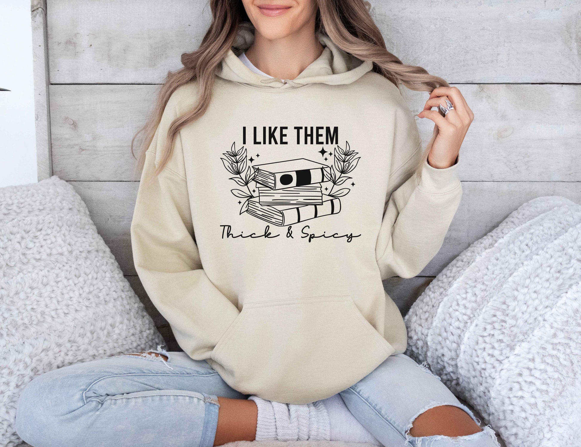 Person wearing a sand hoodie with text and graphic design, sitting on a couch.
