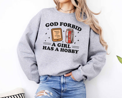 A Gildan 18000 sweatshirt with the saying "god forbid a girl has a hobby"