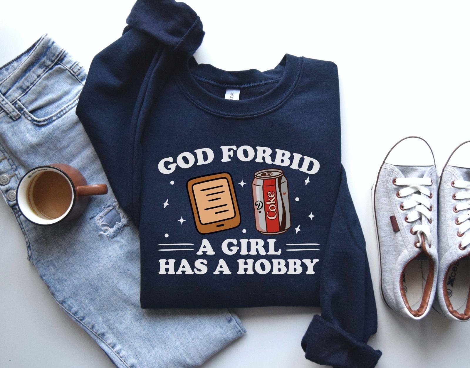 A Gildan 18000 sweatshirt with the saying "god forbid a girl has a hobby"
