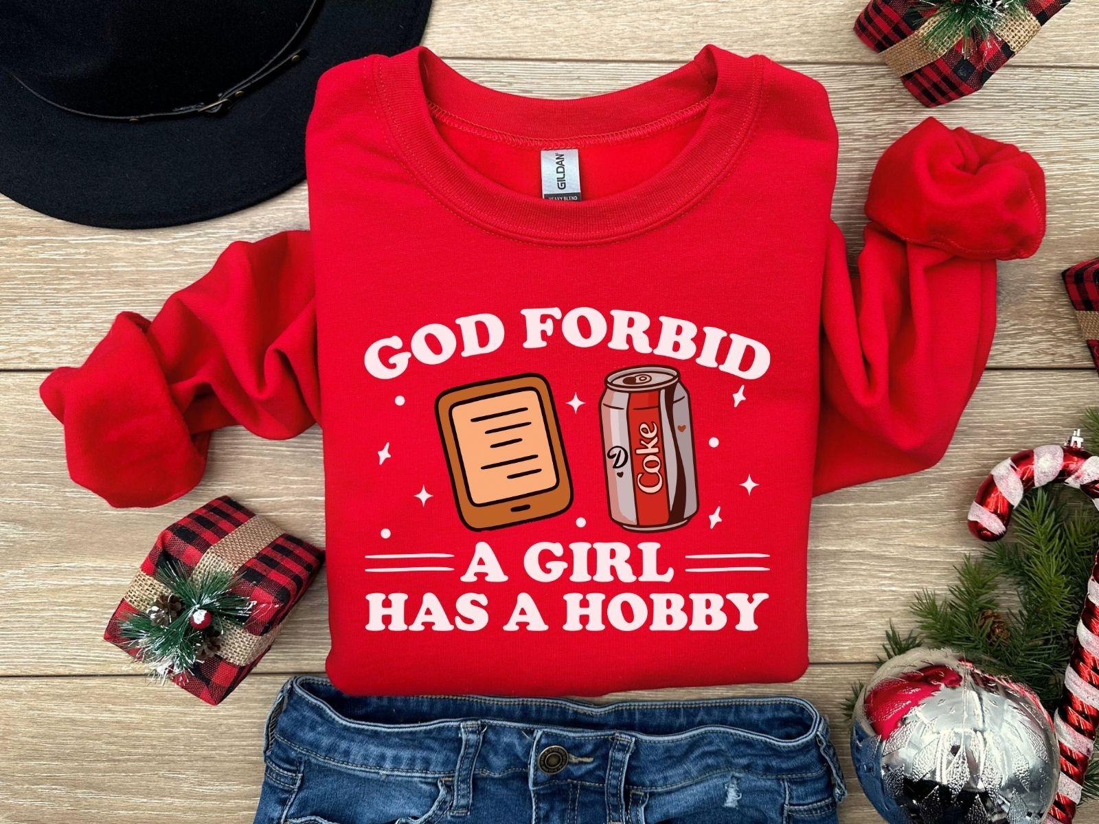 A Gildan 18000 sweatshirt with the saying "god forbid a girl has a hobby"