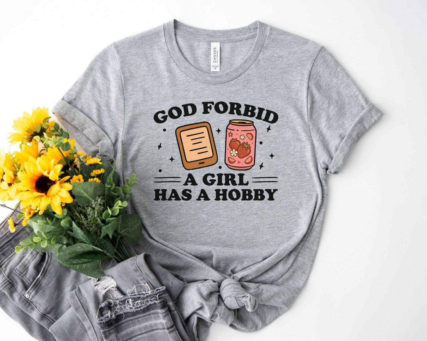 A bella canvas 3001 shirt with the saying "god forbid a girl has a hobby"