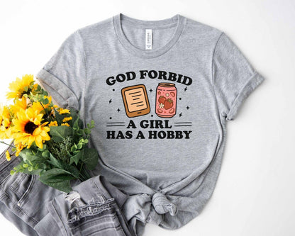 A bella canvas 3001 shirt with the saying "god forbid a girl has a hobby"