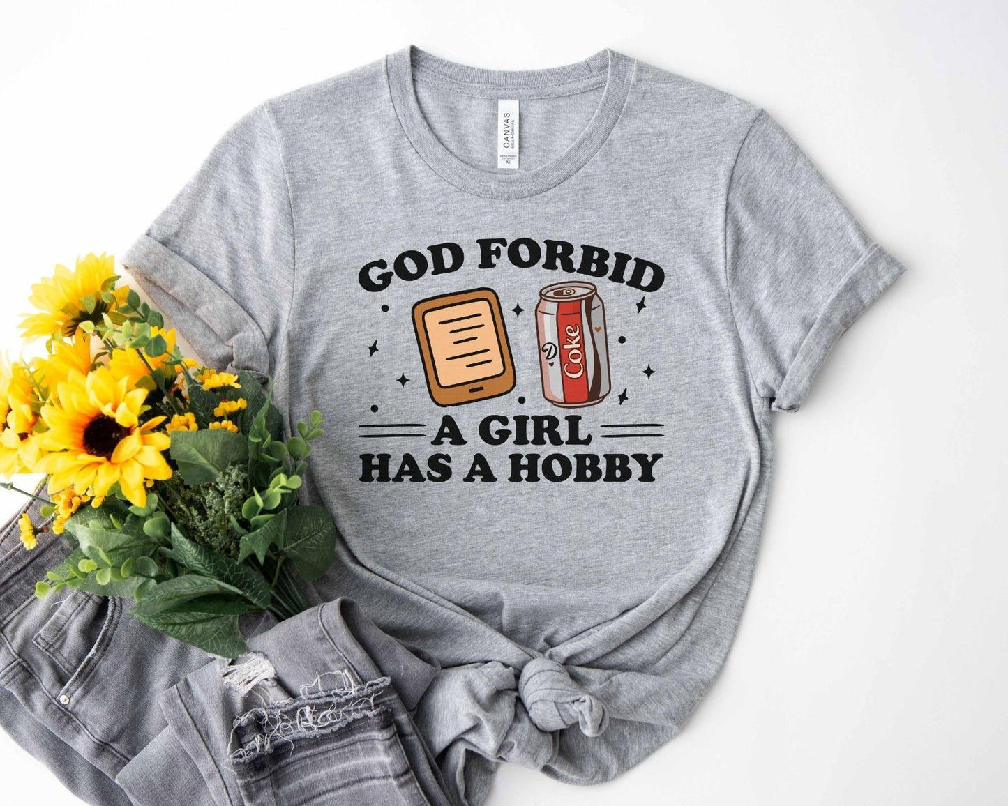 A bella canvas 3001 shirt with the saying "god forbid a girl has a hobby"