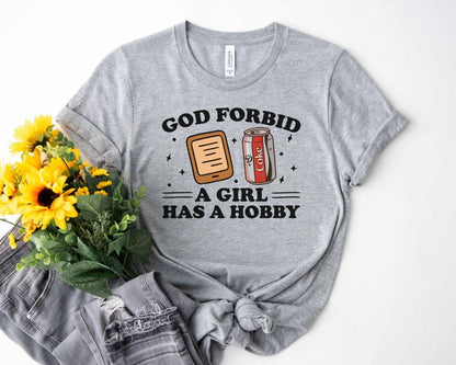 A bella canvas 3001 shirt with the saying "god forbid a girl has a hobby"